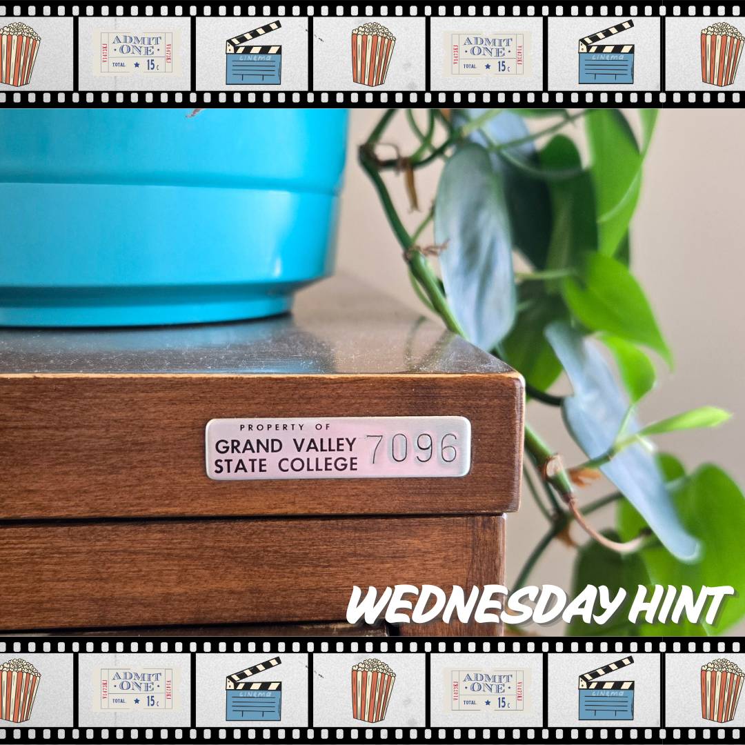 bottom corner of blue pot with leaves on top of a wooden desk
